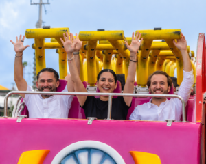 La presidenta municipal Estefanía Mercado levanta las manos mientras prueba un juego mecánico en el Recinto Ferial de Playa del Carmen.
