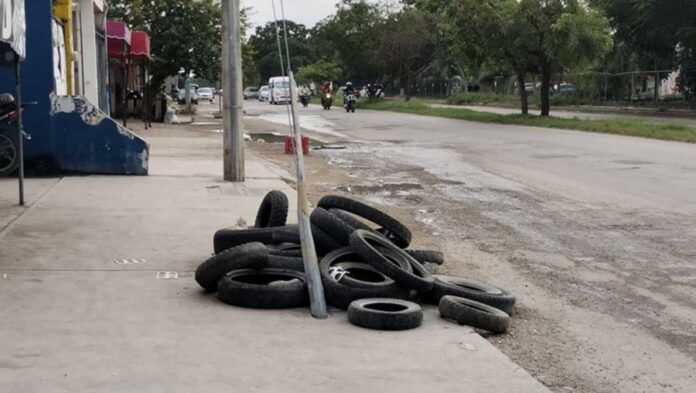 Vecinos de Cancún colocan llantas y fierros para señalizar registros abiertos en las calles de la ciudad.