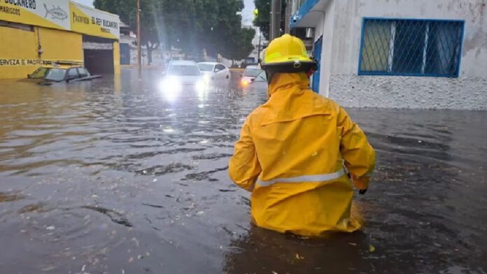 Bombero camina entre una calle inundada durante la tromba que provocó el desbordamiento del río Atoyac en Puebla.