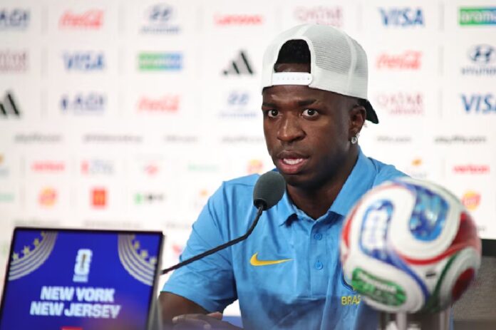 Vinicius Junior atiende a los medios durante una conferencia de prensa del Mundial 2026, sentado frente a un micrófono con el balón oficial del torneo en primer plano.