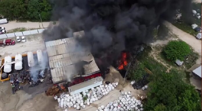 Vista aérea del incendio que consume una bodega cercana a una gasolinera sobre la avenida José López Portillo, en la colonia Tres Reyes de Cancún.
