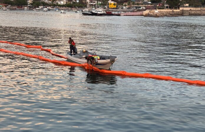 Elementos de la Marina despliegan barreras de contención y embarcaciones especiales tras un derrame de hidrocarburo cerca del muelle turístico de Manzanillo.