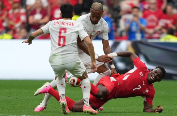 Jugador de Suiza disputa el balón en el suelo ante dos futbolistas de Canadá durante un intenso duelo del Grupo B del Mundial 2026.