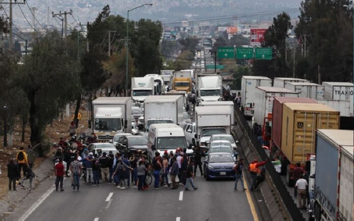 Transportistas realizan un bloqueo en una carretera mientras decenas de vehículos de carga permanecen detenidos durante una protesta.