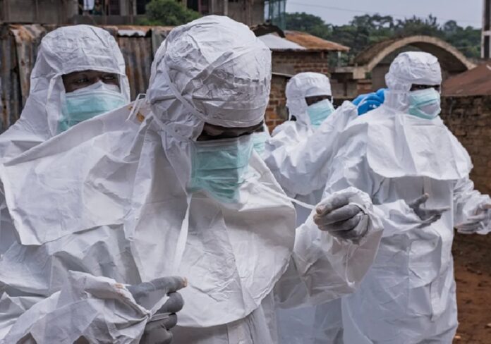 Personal médico con trajes de bioseguridad y mascarillas realiza operativo sanitario preventivo ante posibles casos de ébola durante un brote epidemiológico.