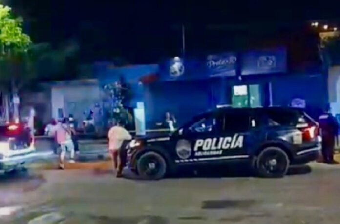 Policías resguardan el exterior del bar El Pretexto en Playa del Carmen tras un ataque armado que dejó daños en la fachada del establecimiento.