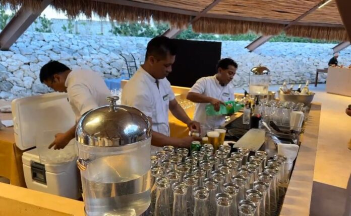 Trabajadores de un hotel en Tulum preparan bebidas y atienden el área de bar durante una jornada laboral en el sector turístico.