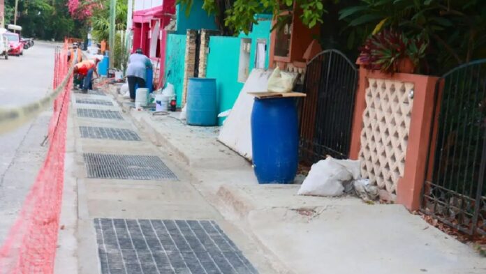 Trabajadores rehabilitan rejillas y captadores pluviales en una vialidad de Isla Mujeres para mejorar el desalojo del agua durante la temporada de lluvias.
