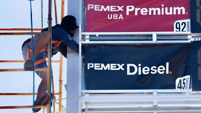 Despachador carga gasolina en estación tras reducción de subsidios federales a combustibles en México.