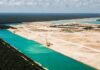 CIADI desestima reclamos de Vulcan por Calica y reduce la indemnización a menos del uno por ciento Vista aérea de terrenos de extracción con grandes cuerpos de agua color turquesa rodeados por vegetación en Playa del Carmen.