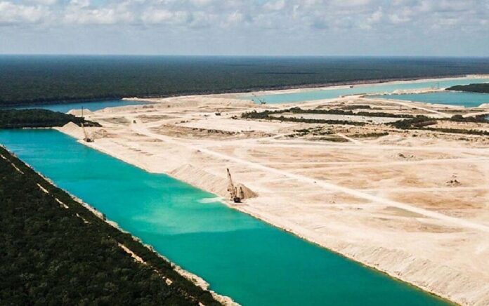 Vista aérea de terrenos de extracción con grandes cuerpos de agua color turquesa rodeados por vegetación en Playa del Carmen.