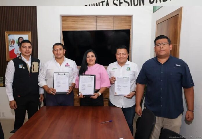 Blanca Merari Tziu Muñoz y representantes de la Congregación Mariana Trinitaria muestran los documentos firmados durante el convenio en una sala de reuniones.