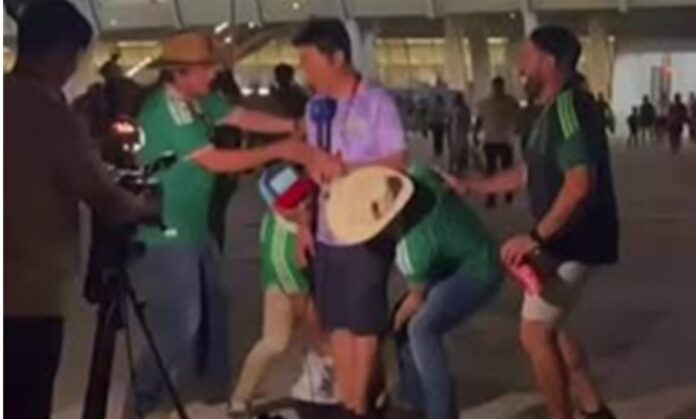 Un periodista surcoreano detiene a varios aficionados mexicanos que intentan cargarlo durante una transmisión en vivo a las afueras del Estadio Monterrey.