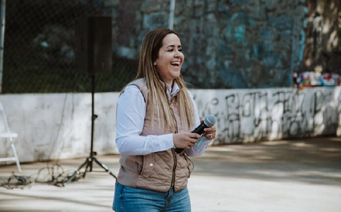 María Quijada sostiene un micrófono durante un evento público al aire libre.