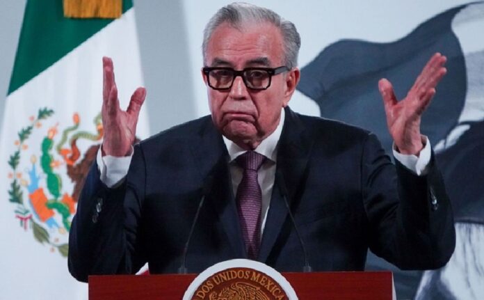 Jorge Romero Herrera ofrece una conferencia de prensa desde un podio con el escudo nacional de México.