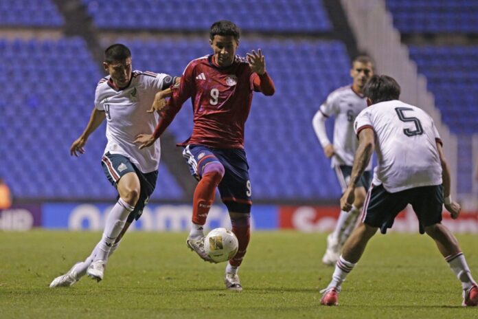 Futbolistas de México y Costa Rica disputan el balón durante un partido sobre la cancha del estadio.