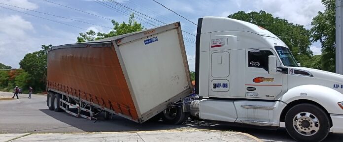 Remolque de un tráiler volcado sobre la carretera con un cargamento de cerveza esparcido tras el accidente.