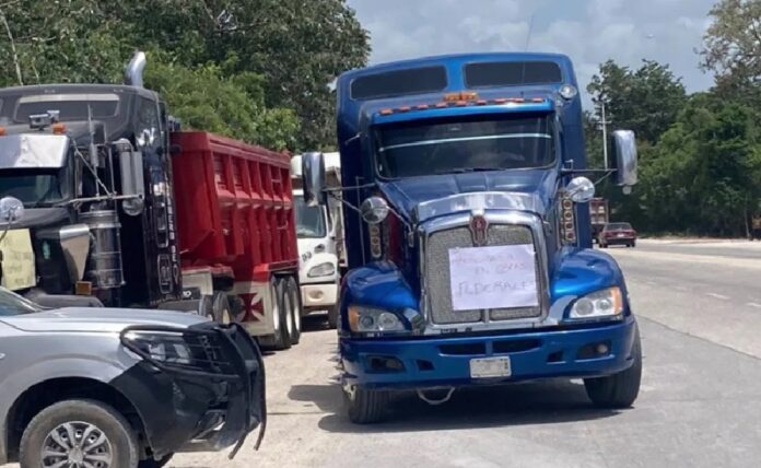 Camiones de carga bloquean la carretera federal 307 durante una protesta de transportistas en Quintana Roo.