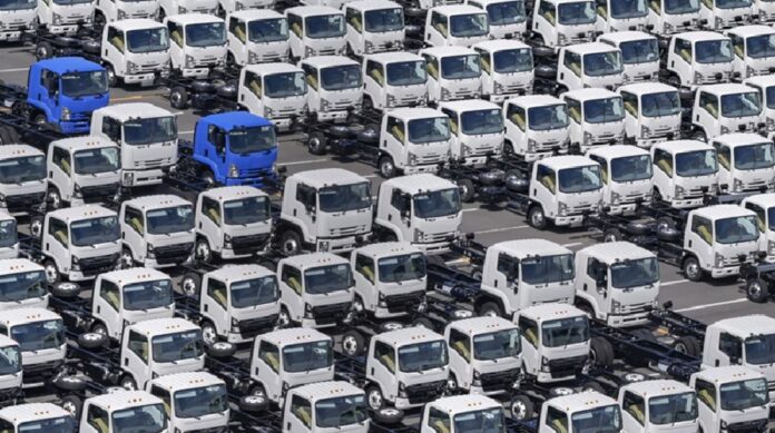 Camiones pesados nuevos permanecen estacionados en un patio de distribución antes de su comercialización.