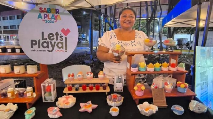 Comerciante exhibe velas artesanales y productos durante el festival Sabor a Playa 2026 en un stand de Playa del Carmen.