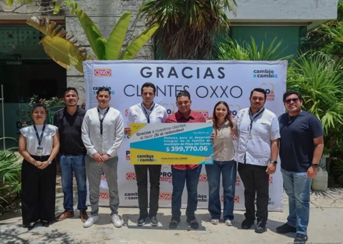 Eduardo Asencio, presidente honorario del Sistema DIF Playa del Carmen, sostiene el cheque simbólico del donativo junto a representantes durante la entrega.