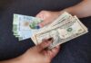 Dólar inicia la jornada estable en medio de expectativas por el T-MEC Dos personas sostienen billetes de dólares estadounidenses y billetes mexicanos de 200 pesos.