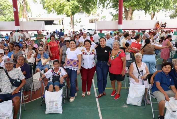 Blanca Merari Tziu Muñoz con beneficiarios durante la entrega de despensas en una cancha techada de Puerto Morelos.