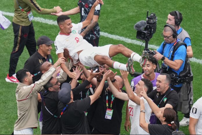 Jugadores y cuerpo técnico de Marruecos levantan en hombros a Azzedine Ounahi mientras celebran la clasificación en la cancha.