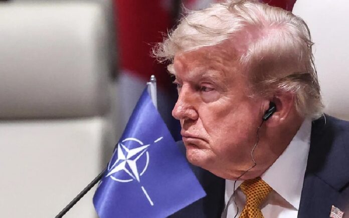 Donald Trump escucha una intervención durante una reunión internacional con un audífono colocado en el oído derecho.