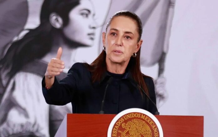La presidenta Claudia Sheinbaum ofrece una conferencia desde un podio con el escudo de los Estados Unidos Mexicanos.
