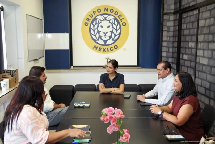 Estefanía Mercado sostiene una reunión de trabajo con representantes de Grupo Modelo en una sala de juntas.