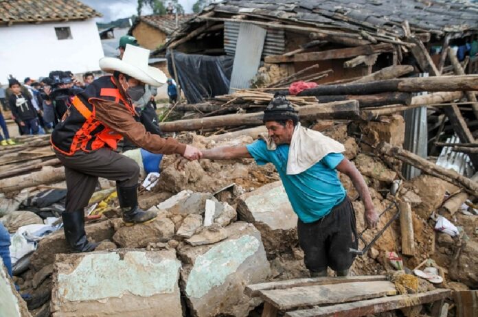 Un rescatista ayuda a un hombre entre los escombros de viviendas dañadas tras el sismo en una comunidad de Perú.