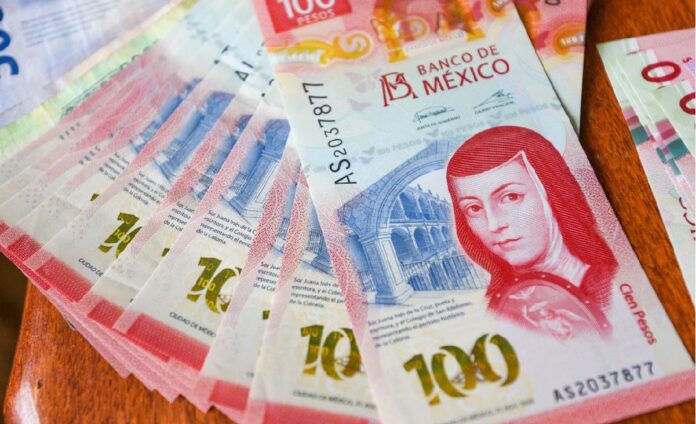 Billetes mexicanos de 100 pesos colocados sobre una superficie de madera.