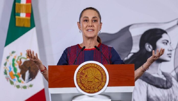 La presidenta Claudia Sheinbaum ofrece una conferencia desde un atril con el escudo nacional, mientras gesticula durante su mensaje.