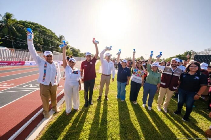 Autoridades estatales sostienen piezas conmemorativas durante la inauguración de la pista certificada de atletismo en la Unidad Deportiva Bicentenario de Chetumal.