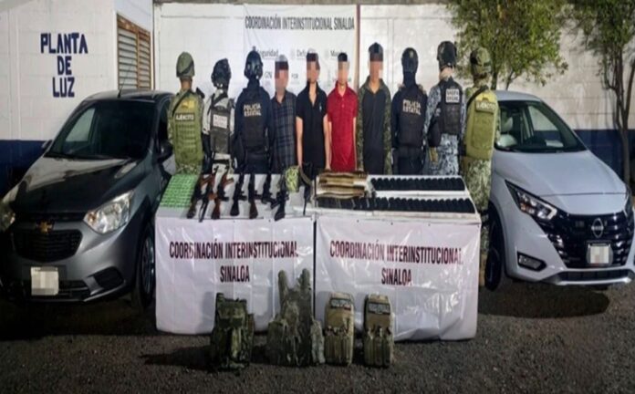 Cuatro personas detenidas permanecen custodiadas por elementos de seguridad frente a armas, cartuchos, equipo táctico y dos vehículos asegurados.
