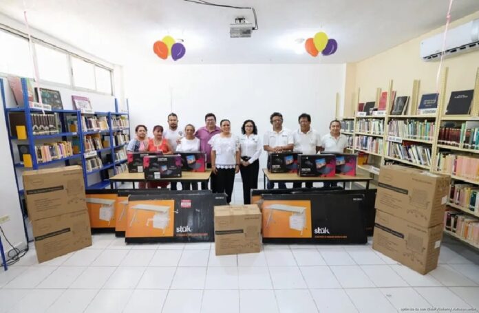 Autoridades municipales posan dentro de una biblioteca junto al equipo de cómputo, escritorios y mobiliario entregado.
