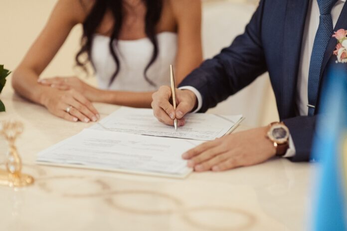Pareja firma documentos para contraer matrimonio civil, tras la reforma en Quintana Roo que elimina restricciones relacionadas con discapacidad y enfermedades.