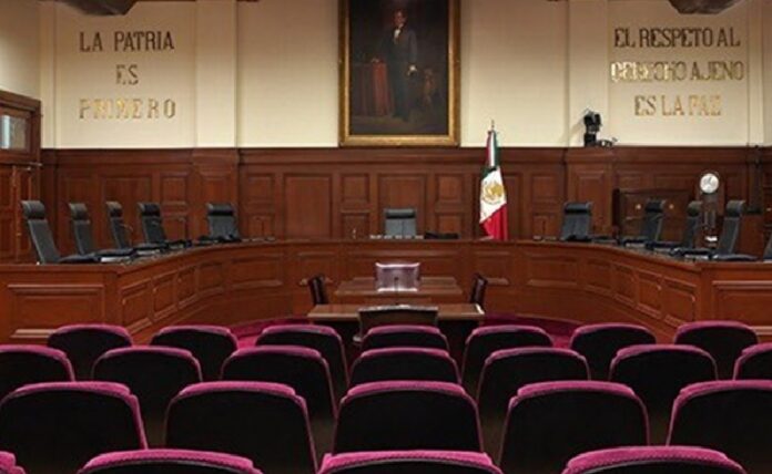 Sala de sesiones de la Suprema Corte de Justicia de la Nación con el estrado, la bandera de México y butacas.
