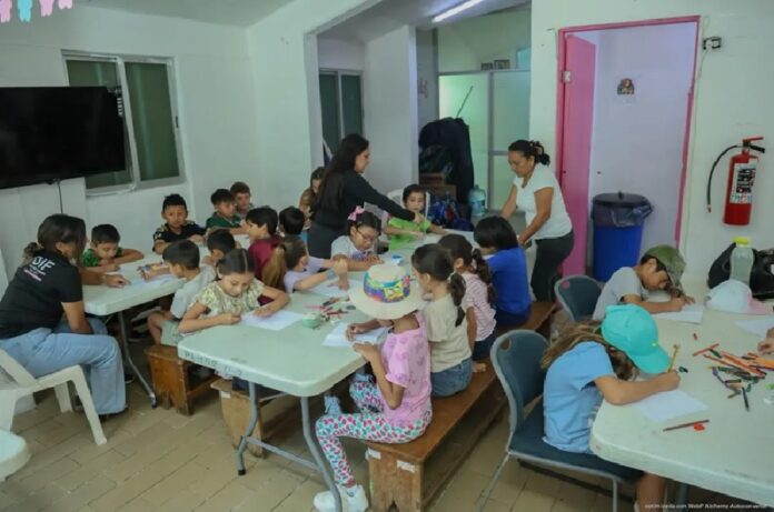 Niñas y niños participan en actividades de dibujo y manualidades durante el curso de verano del DIF Playa del Carmen.
