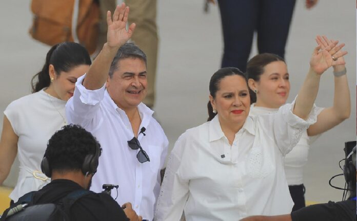 Juan Orlando Hernández saluda junto a su esposa Ana García durante un acto público en Honduras.