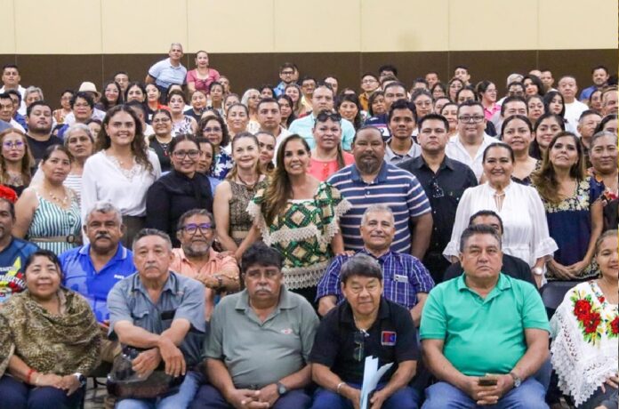 Mara Lezama junto a numerosas personas reunidas en un auditorio.