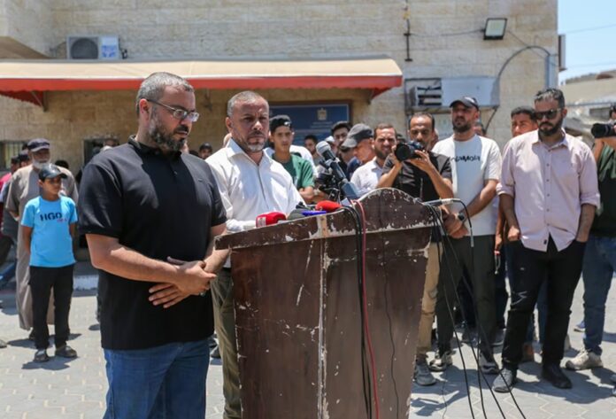 Portavoces de Hamás ofrecen una conferencia de prensa frente a un grupo de periodistas y asistentes en una calle de Gaza.