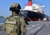 FGR investiga red que ingresó 144 millones de litros de huachicol fiscal, revela Reforma Elementos de la Secretaría de Marina resguardan un buque tanque atracado en un puerto, mientras vehículos de carga permanecen en el muelle.