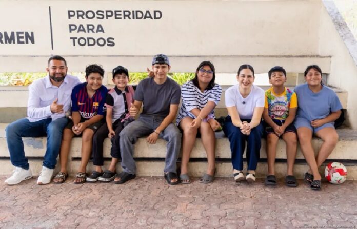 Estefanía Mercado con varios niños, adolescentes y un funcionario en un espacio deportivo.