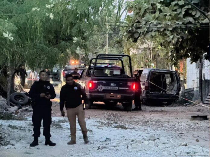 Policías municipales resguardan una calle de terracería mientras patrullas permanecen en la escena de un homicidio.