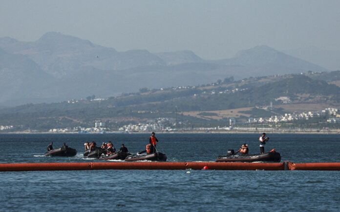 Embarcaciones de la Guardia Civil patrullan junto a una barrera flotante instalada frente a la costa de Ceuta.