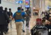Estados Unidos eleva hasta 40 las detenciones diarias de migrantes en aeropuertos Agentes del Servicio de Inmigración y Control de Aduanas (ICE) recorren el área de pasajeros de un aeropuerto mientras viajeros esperan con su equipaje.